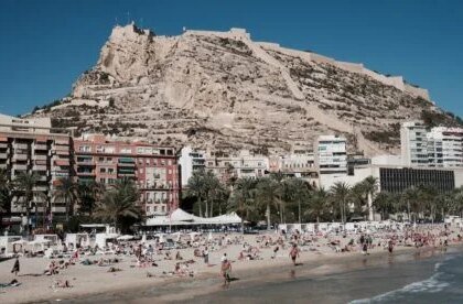 Alicante beach and castle with a mix of foreign and residents on the beach.